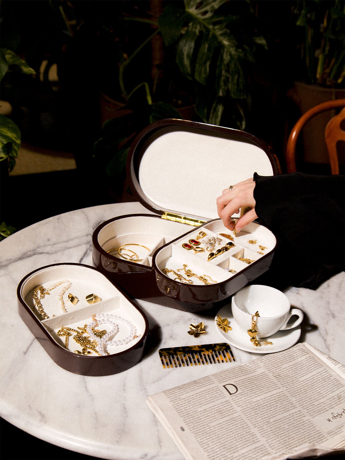 Brunt smyckeskrin från misou som är öppet på marmor med hand