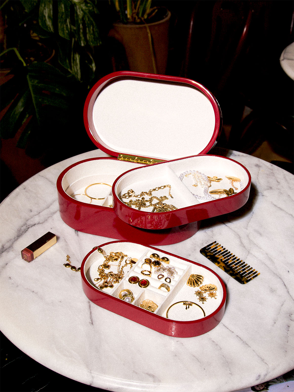 Rött smyckeskrin från misou som är öppet med brickor på ett marmorbord